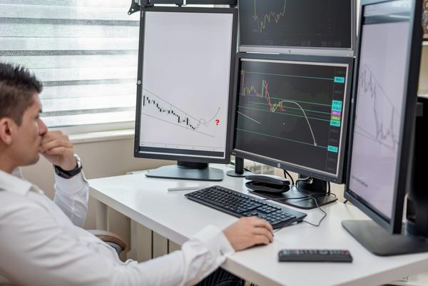 Analyst working at a desk with several crypto trading monitors