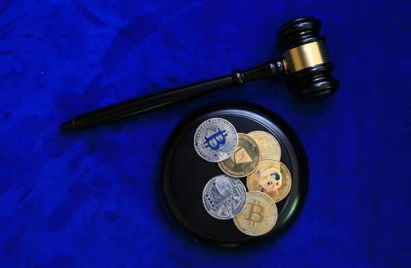 Judge gavel next to crypto coins on a blue background