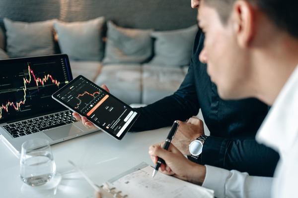 Support specialists reviewing crypto charts on a laptop and phone