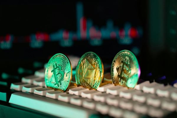 Crypto coins glowing green on a keyboard under neon light