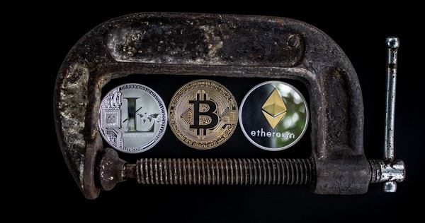 Metal clamp holding Litecoin, Bitcoin and Ethereum coins