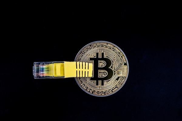 Bitcoin coin with a yellow network cable on a digital code background