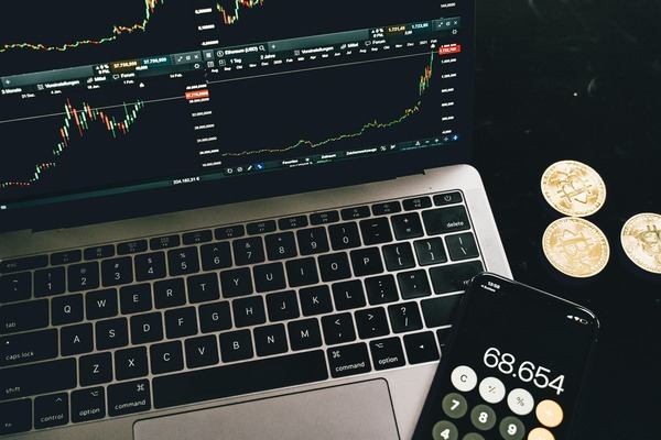Laptop with crypto price chart, calculator and coins on a dark desk