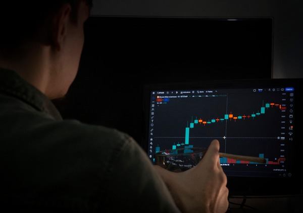 User checking a crypto chart on a monitor in a dark room