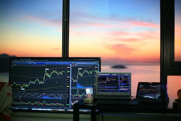 Crypto trading screens on a desk at sunset by the window