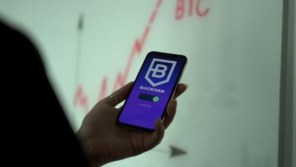 Phone displaying a blockchain app in a hand