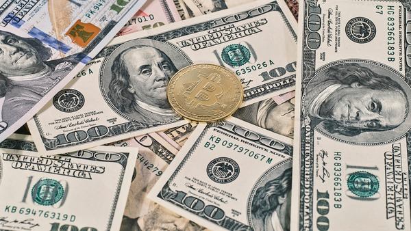 Gold crypto coin lying on a pile of US dollar bills