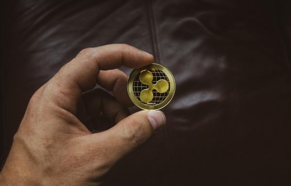 Hand holding a gold Ripple coin close-up