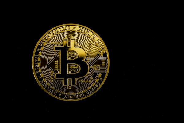 Gold Bitcoin coin glowing on a black background